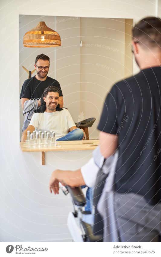 Vertical photo of barber drying hair with a towel to a client in front of a mirror vertical saloon chair products barbershop hairdryer furniture work service