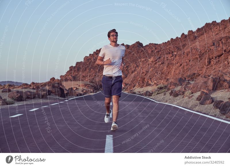 Excited man running on road against mountain landscape journey volcano asphalt surrounded rocky el teide tenerife spain canary island adventure distance sky