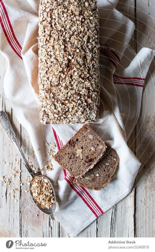 Loaf of ryecorn bread on towel fresh spoon grain napkin cloth table meal food cuisine kitchen home snack cereal rustic baked scrumptious fabric healthy