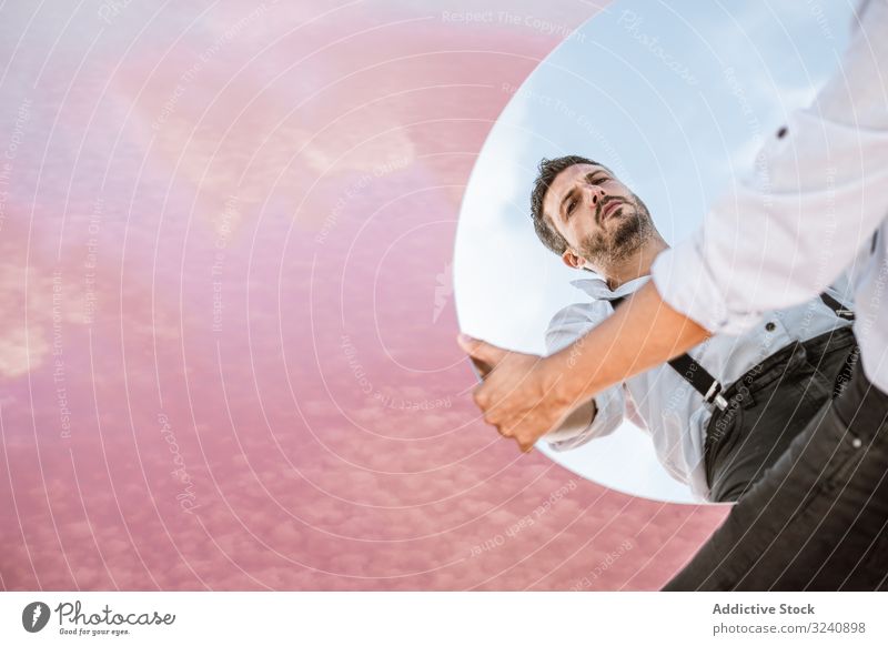 Stylish man holding mirror with reflection stylish pensive white shirt suspenders stand blue sky lifting carrying handsome oval surreal usa concept modern young