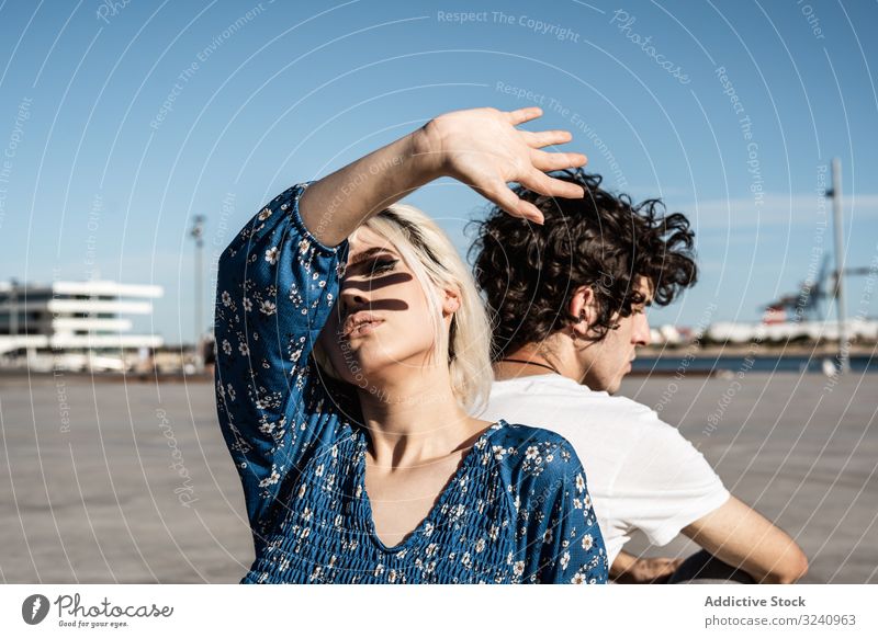 Trendy couple sitting and contemplating on street in daylight dream affection confident shadow cover pensive contemplate hand trust love look calm think