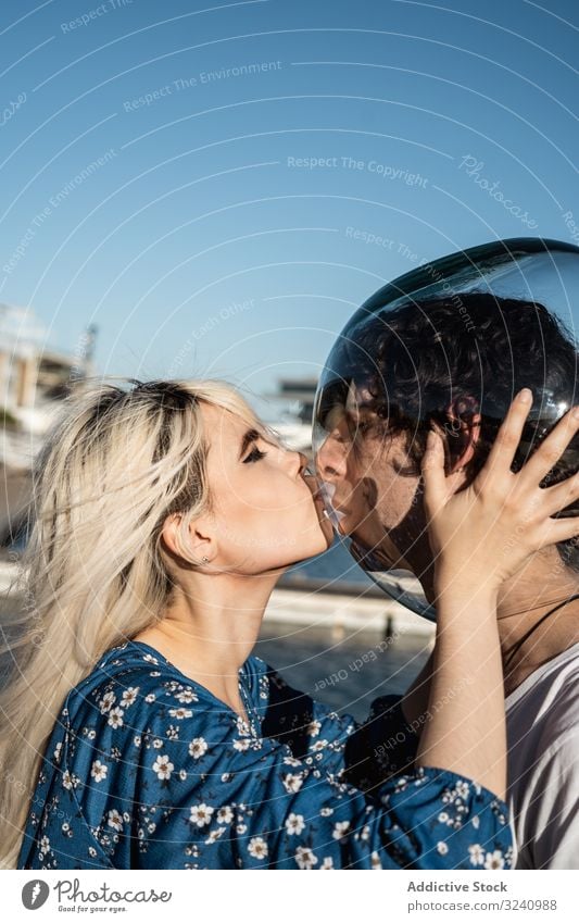 Adult woman touching fish bowl on head of tranquil boyfriend and showing tongue couple introvert feelings concept isolation relationship serenity solitude