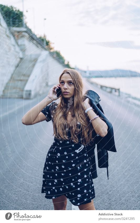 Long haired stylish woman speaking on smartphone phone call city serious news road receive budapest using focused conversation communication talking mobile