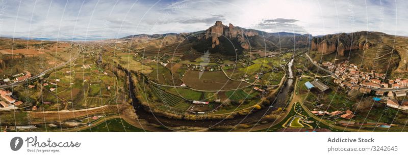 Drone view of Islallana, La Rioja mountain rural town picturesque slope hill cliff green grassy range building house road infrastructure valley distant field