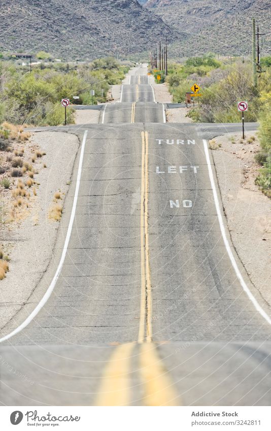 Asphalt road at scenic mountain valley and power line asphalt rural field dusty remote sunny landscape nature travel rock tourism usa hill curve peak summer