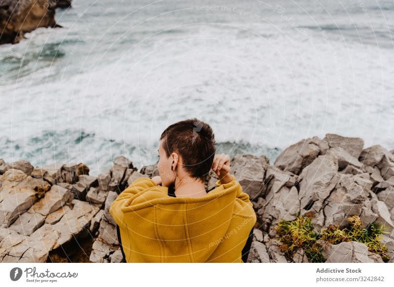 Woman in yellow hoodie on stony shore woman solitude travel wave stone watching dream harmony contemplation lonely thoughtful sea ocean horizon freedom