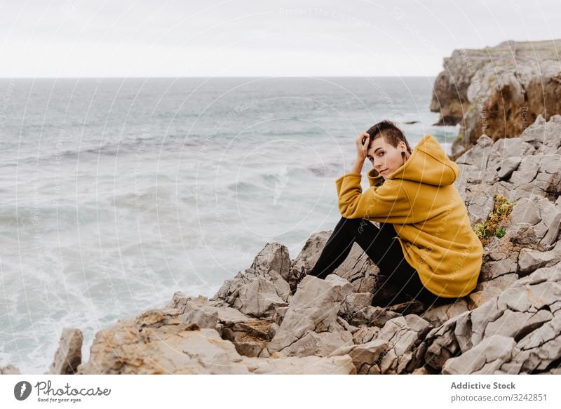 Woman in yellow hoodie on stony shore woman solitude travel wave stone watching dream harmony contemplation lonely thoughtful sea ocean horizon freedom