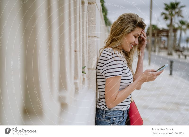 Woman using phone on city street woman read happy smile young cheerful female satisfied joyful laugh positive smartphone mobile cellphone wireless communication