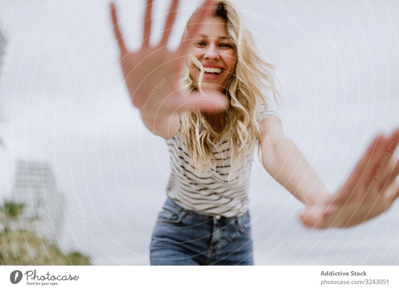 Cheerful woman hiding from camera hiding face joyful shy blonde happy city walk enjoy fun casual young female laugh smile stand beautiful pretty lovely avoid