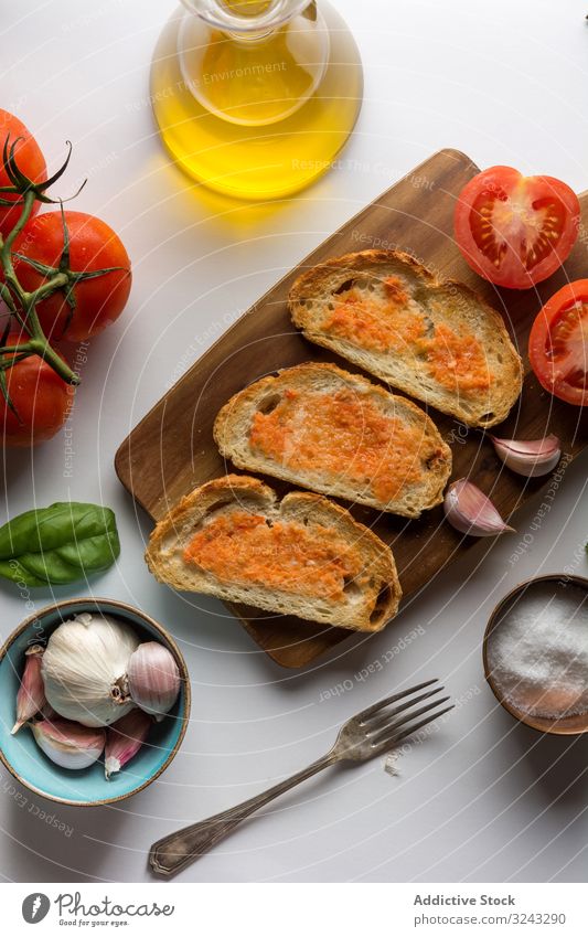 Spices and vegetables near toasts sauce ingredient spice tomato salt garlic basil oil bread cutting board food snack delicious tasty bruschetta yummy delectable