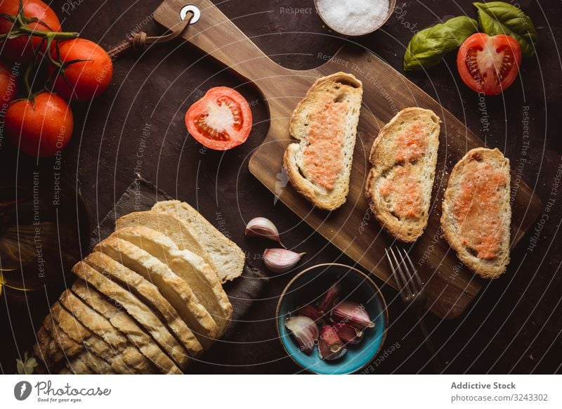 Spices and vegetables near toasts sauce ingredient spice tomato salt garlic basil oil bread cutting board food snack delicious tasty bruschetta yummy delectable