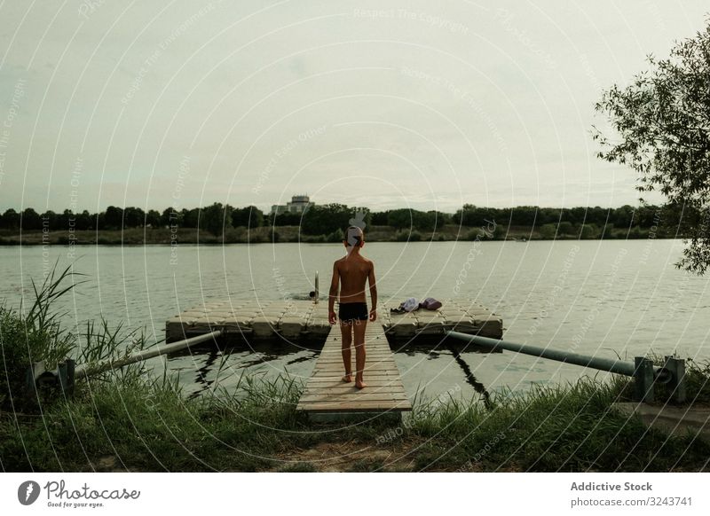 Child in swimming trunks walking along pier to water child vacation harmony weekend solitude nature peace calm kid rest little enjoyment plant pleasure summer