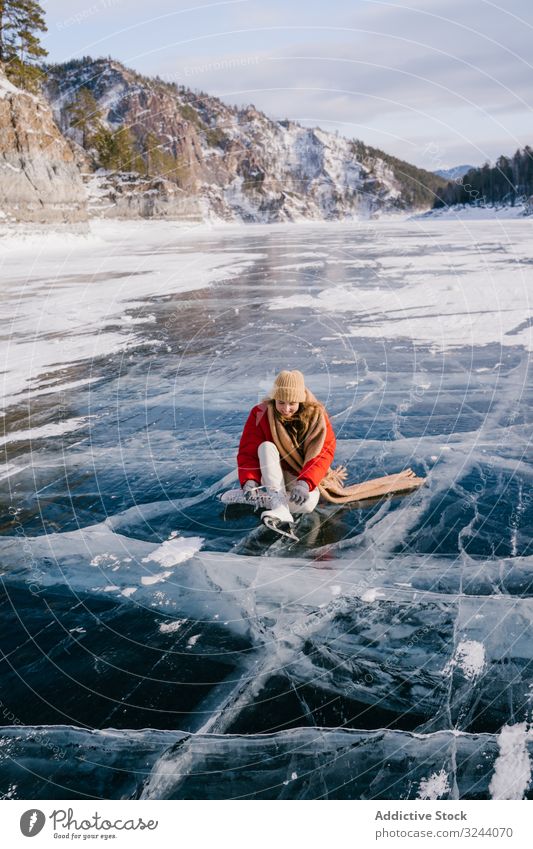 Woman sitting on frozen river and tying the shoelaces woman snow boots skates putting on winter change siberia cold sportswear russia female white adventure