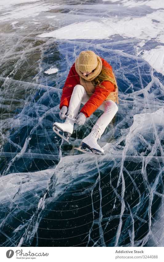 Woman sitting on frozen river and tying the shoelaces woman snow boots skates putting on winter change siberia cold sportswear russia female white adventure