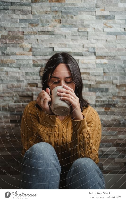 Woman drinking hot tea at home woman mug sweater coffee sit floor jeans female cup beverage young hold relax enjoy recreation warm up cold pullover room house