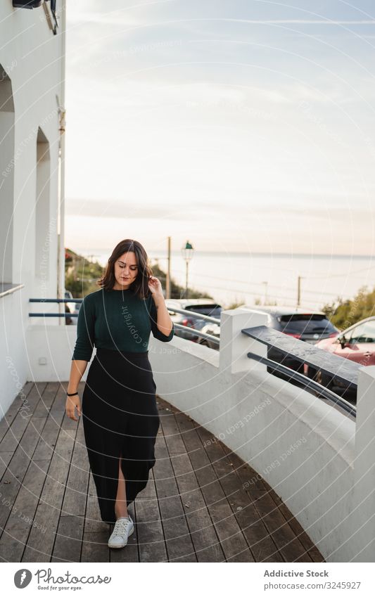 Pensive woman walking on balcony house coast riverside seaside thoughtful pensive casual young calm home wooden handrail building rest relax female brunette