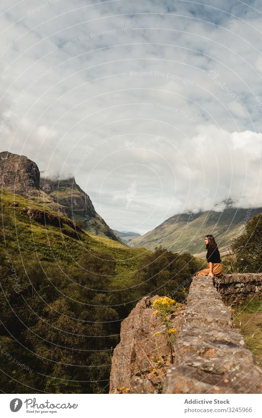 Serene tourist enjoying view of tranquil green valley in cloudy weather highland cliff woman environment height trip adventure freedom female mountain landscape