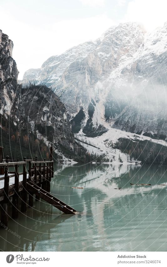 Wooden pier on stilts on lake near mountains bridge wooden reflection nature travel water landscape sky scenery view tourism vacation clouds holiday adventure