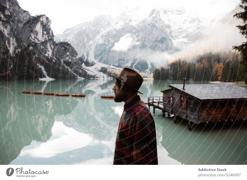 Resting man in casual wear delighting in views near lake and mountains tourism house water boat fog cloudy mist travel landscape vacation adventure nature