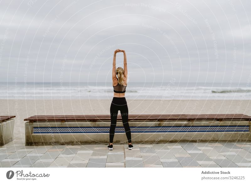 Faceless lady gymnast in sports clothing stretching before exercise at seaside woman seashore athletic fit young healthy workout tracksuit nature morning female