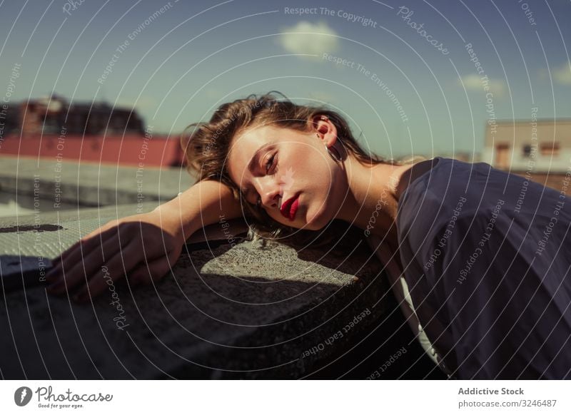 Beautiful female model in casual clothing at roof posture fashionable stylish woman young teenager leaning rocked fence sunny summer emotionless red lips