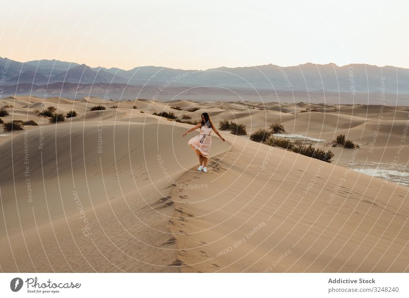 Back view of young woman walking in desert leaving footprints in dry sandy dunes in Death Valley death valley wanderlust travel vacation direction holiday