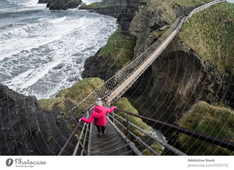 Woman crossing rope bridge leading to rocky island woman sea walk ocean northern ireland coast carric a rede shore water landscape female confidence courage