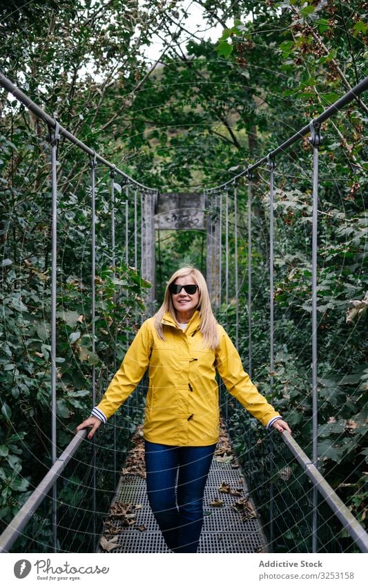 Cheerful female tourist standing on hanging bridge in summer woman footbridge forest cheerful vacation suspension summertime tourism travel journey nature