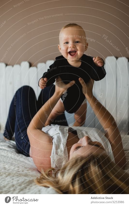 Mother playing with baby on bed mother excited home lift care family woman kid child nursery fun bonding innocence happy joy cheerful delighted optimistic love