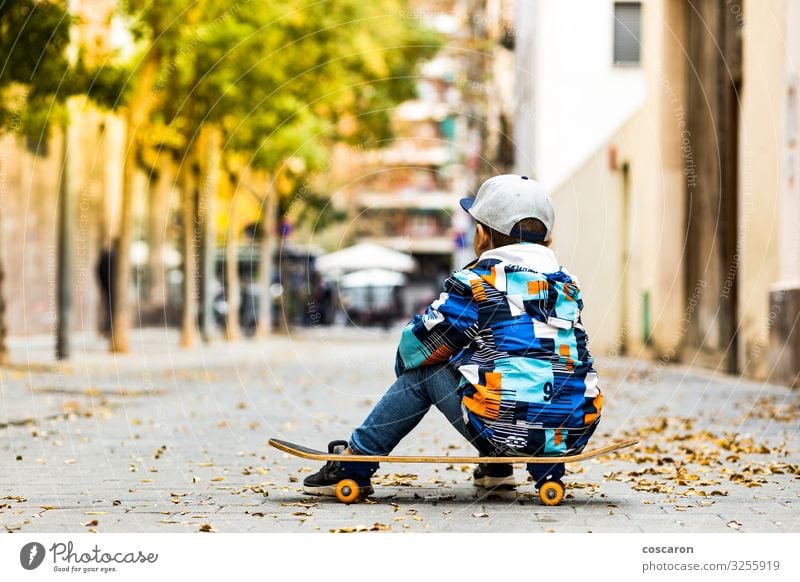 Cute little kid sitting on his sakteboard Lifestyle Style Joy Happy Beautiful Leisure and hobbies Playing Board game Summer Winter Sports Child School