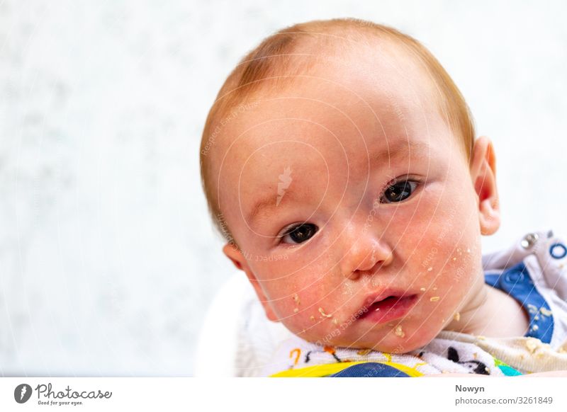 Porridge on the face at breakfast Eating Baby Curiosity Interest Surprise Appetite To enjoy bib boy bright copy space copyspace dirty food ginger head hungry