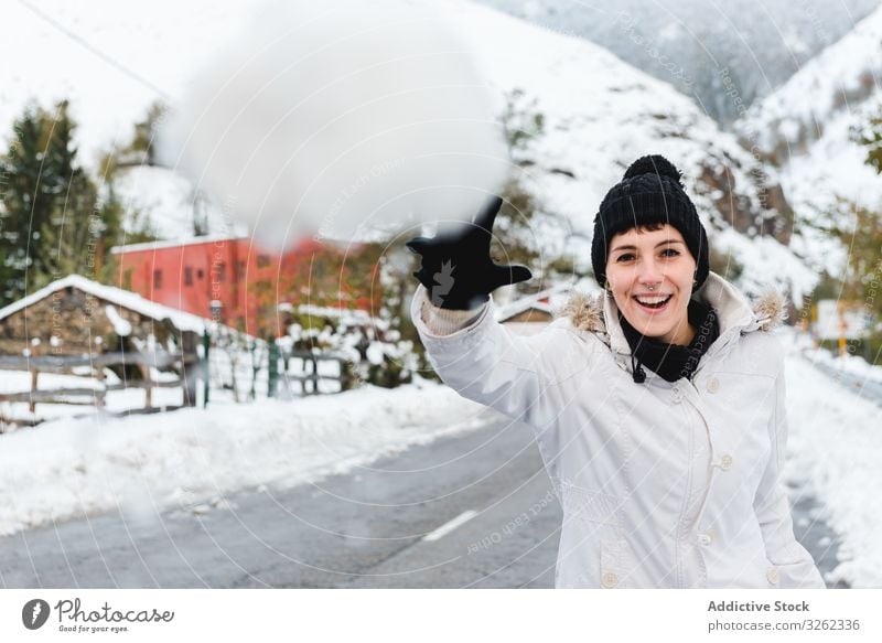 Smiling woman playing with snow in countryside snowball winter smile joy mountain rest resort holiday nature village rural cold fun game vacation tree white