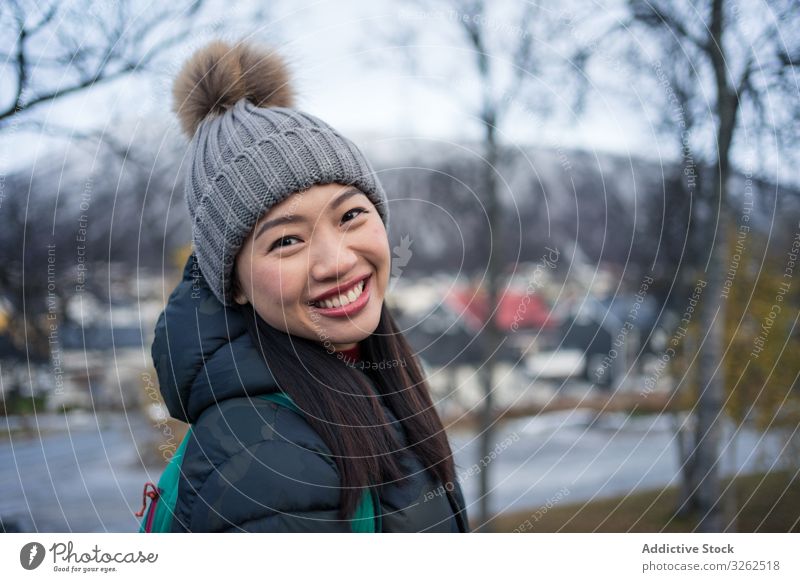 Joyful ethnic tourist on road bridge against modern building with unusual architecture at foothill in cold weather street church happy woman smile travel