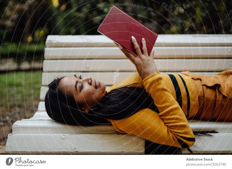 Graceful long haired Asian woman reading book on bench in park stylish white fashion model elegant asian vogue smart trendy lady fashionable brunette study