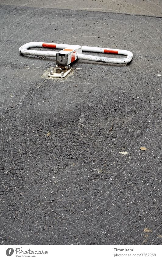 The lying parking lot barrier Parking lot lock blocking Metal reserve flipped open unauthorized Places Asphalt Gray Red White Deserted Exterior shot