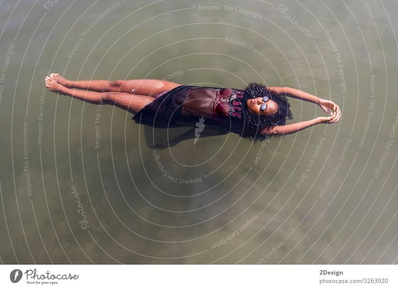 Beautiful young African woman floating at a pool of water Lifestyle Joy Relaxation Swimming pool Leisure and hobbies Playing Vacation & Travel Summer Sun Dive