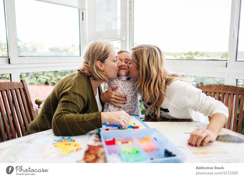 Woman playing board game with daughter and granddaughter family multi generational mother daughters together fun happy grandmother woman girl table female child