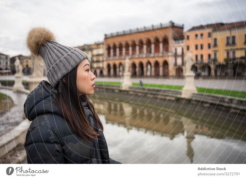 Asian woman on vacation in warm wear strolling at beautiful park with ancient building and pond sightseeing city historical old architecture tourism travel