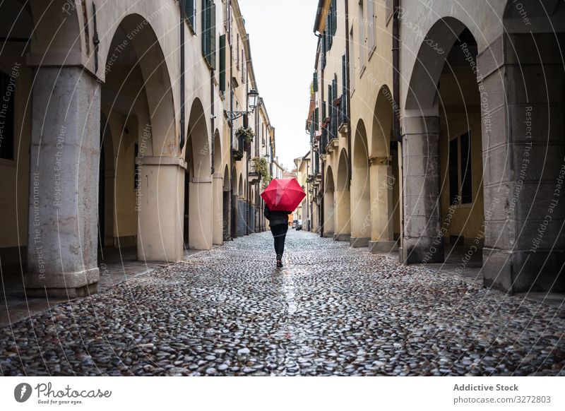 Tourist with umbrella walking at city street on rainy weather person tourist strolling explore interest wet building old beautiful architecture travel