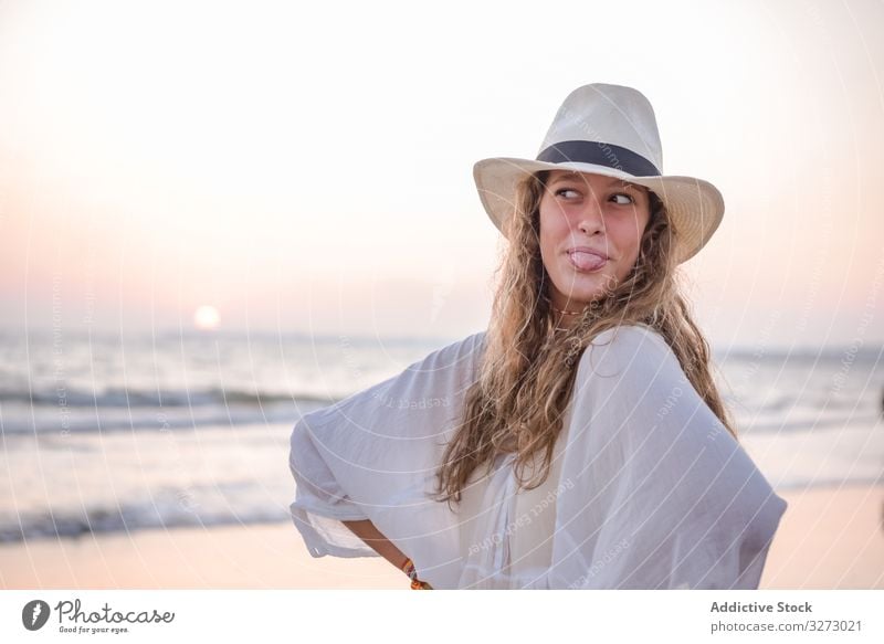 Charming woman in light white dress on wavy beach sea traveling seaside tourism charming vacation hat curly holiday summer freedom journey young relaxing