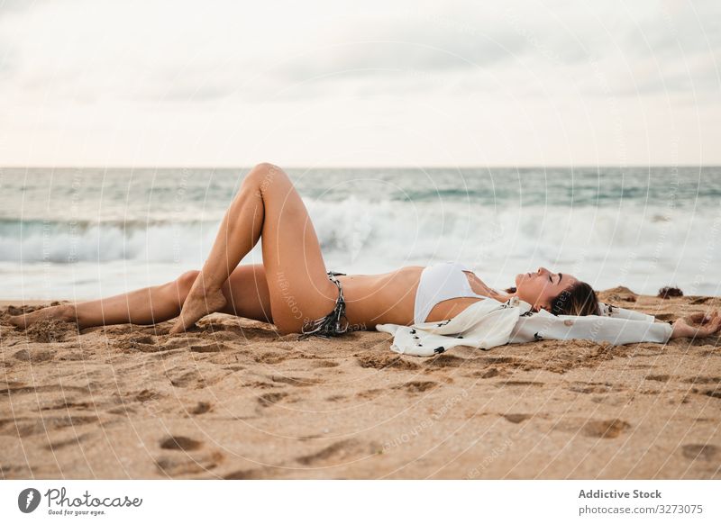 Woman resting on sandy beach on cloudy day woman walk sea water sky vacation female resort weekend summer lifestyle relax swimwear bikini blouse lady ocean sit