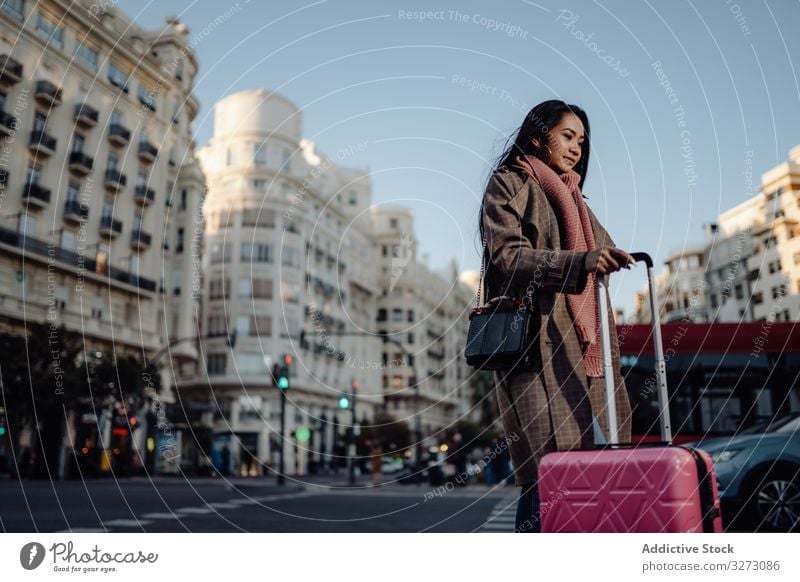 Asian tourist on sidewalk in city woman suitcase road ethnic smile sunny daytime female visit street asian luggage baggage travel trip young urban town pavement