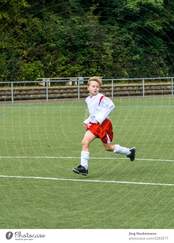 young soccer player runs over the football ground Joy Happy Playing Club Disco Sports Soccer Child Human being Boy (child) Infancy Youth (Young adults) Footwear