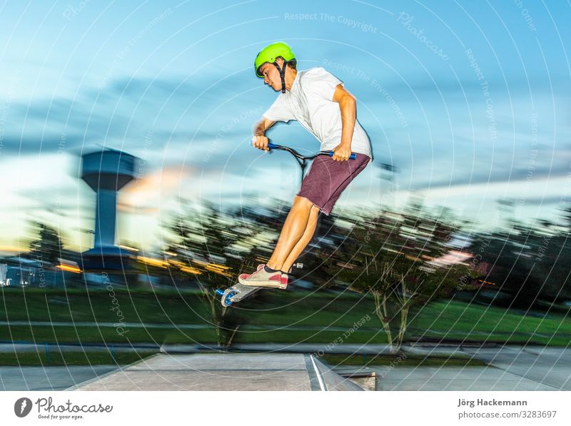 boy has fun riding his push scooter at the skate park Lifestyle Joy Leisure and hobbies Sports Boy (child) Youth (Young adults) Movement To enjoy Jump