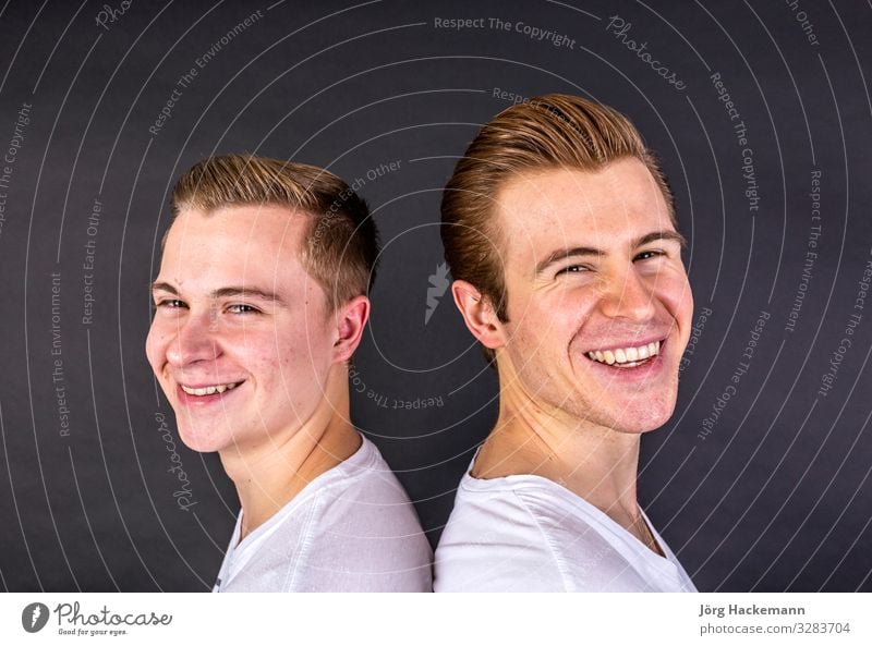 two teenage boys standing back to back and have fun Joy Happy Face Boy (child) Family & Relations Friendship Couple Youth (Young adults) Smiling Laughter Stand