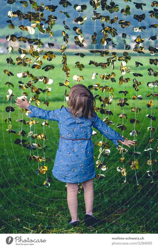 Little girl on a meadow under a golden-yellow garland Girl 3 - 8 years Child Infancy Summer Dress Brunette Playing Happy Natural Curiosity Blue Gold Green Joy