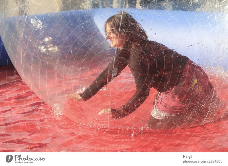 Woman kneels happily in a big plastic ball in the water basin Human being Feminine Adults 1 45 - 60 years Clothing T-shirt Skirt Brunette Long-haired bubble