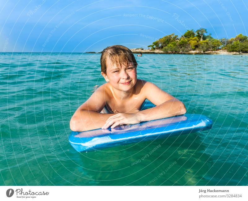 boy is swimming on his surfboard Joy Happy Relaxation Vacation & Travel Beach Ocean Island Child Youth (Young adults) Nature Landscape Sky Horizon Warmth