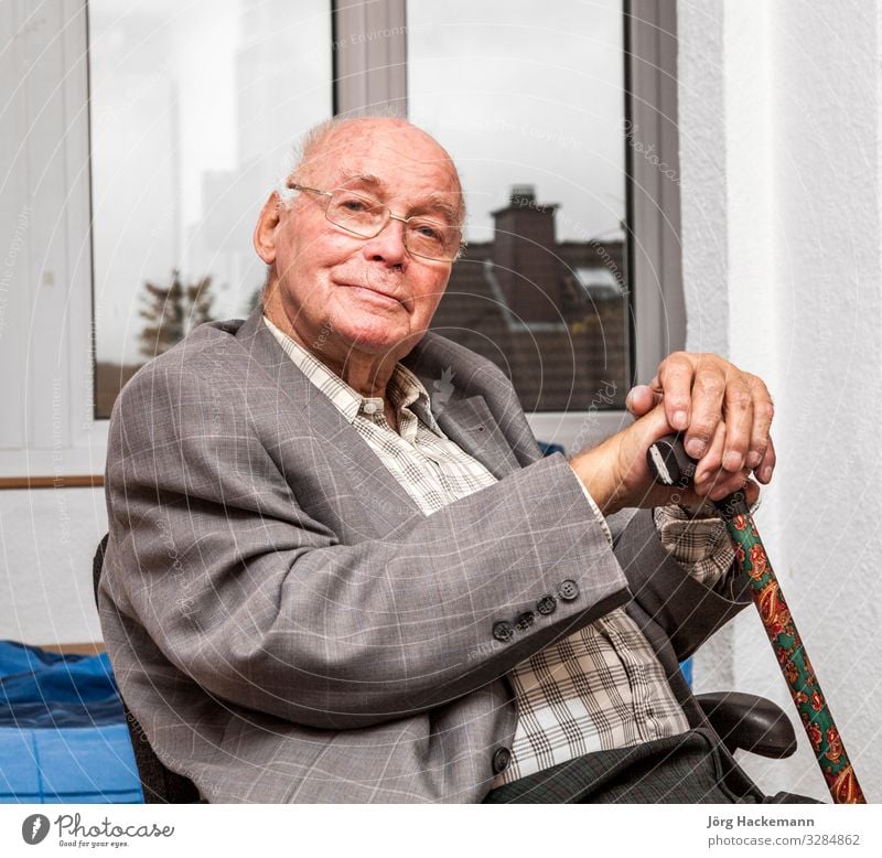 smiling senior man sits at the chair and looks happy Lifestyle Joy Happy Face Relaxation Calm Chair Retirement Human being Man Adults Jacket Old Smiling Sit