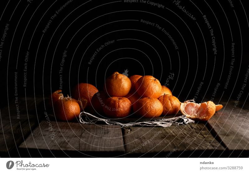 pile of unpeeled round ripe orange mandarin Fruit Dessert Nutrition Vegetarian diet Juice Plate Table Wood Fresh Natural Juicy Yellow Gray Black citrus food